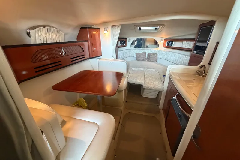 Slide: The Image of Interior of 2005 Sea Ray Sundancer 280, featuring cozy seating, table, and compact kitchen area. - 27