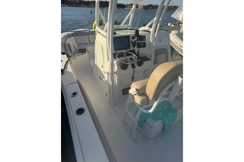 Slide: The Image of 2015 Sea Fox 249 Avenger boat interior with helm and seating, docked by the water. - 5