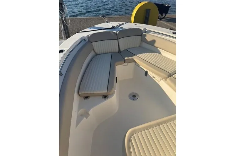 Slide: The Image of 2015 Sea Fox 249 Avenger boat interior with cushioned seating, docked by the water. - 8