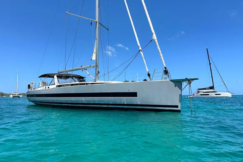 The Image of 2019 Beneteau Oceanis Yacht 62 sailing on clear turquoise waters under a bright blue sky. - 0