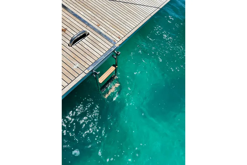 Slide: The Image of Teak deck and swim ladder of 2019 Beneteau Oceanis Yacht 62 over turquoise water. - 11