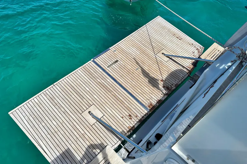 Slide: The Image of Teak swim platform on 2019 Beneteau Oceanis Yacht 62, above clear turquoise water. - 12