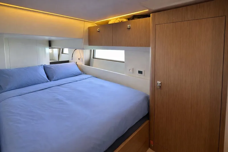Slide: The Image of Luxurious bedroom interior of 2019 Beneteau Oceanis Yacht 62 with blue bedding and wooden accents. - 27
