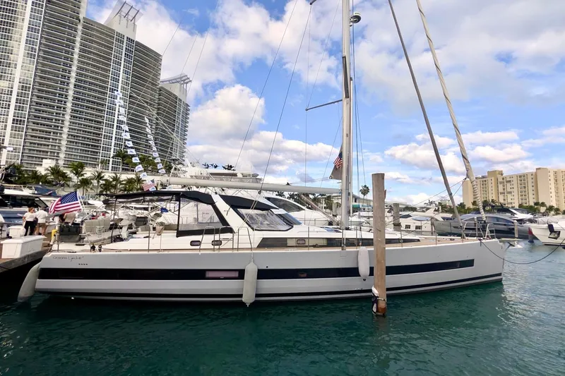 Slide: The Image of 2019 Beneteau Oceanis Yacht 62 docked in a marina with cityscape background. - 5