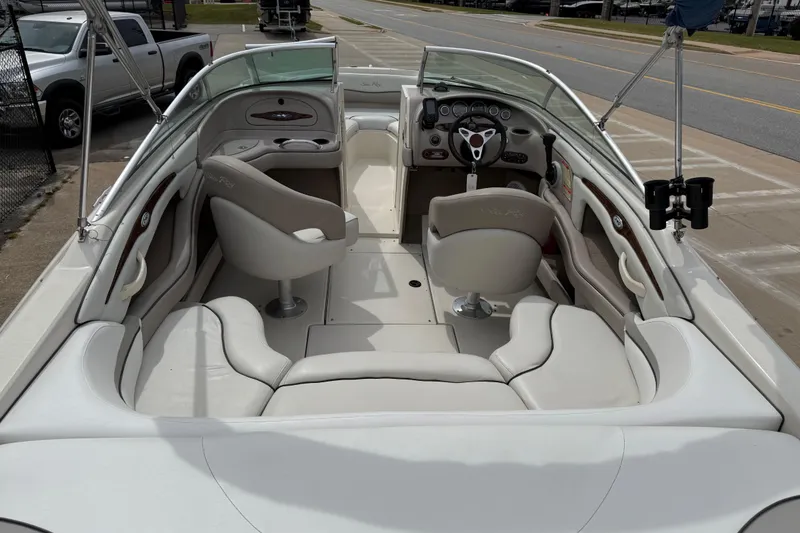 Slide: The Image of 2003 Sea Ray 240 Bow Rider interior with seating and steering wheel, parked on pavement. - 13