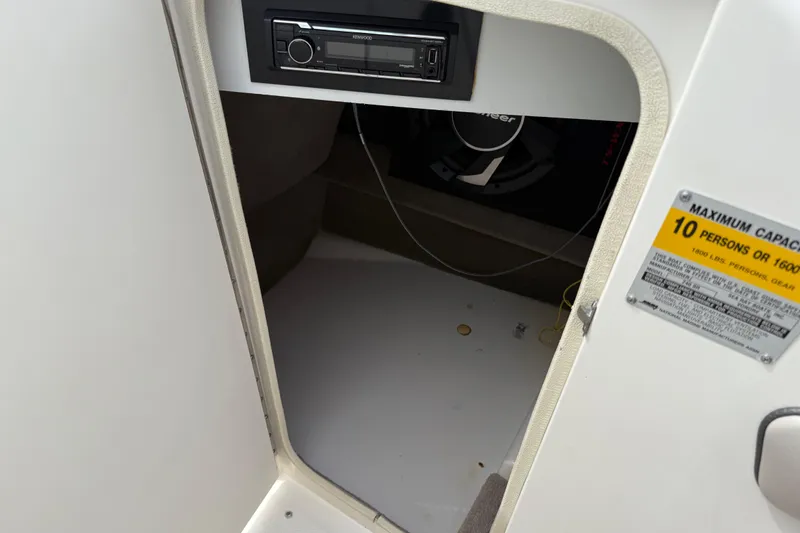 Slide: The Image of Storage compartment in a 2003 Sea Ray 240 Bow Rider with stereo system and capacity label. - 37