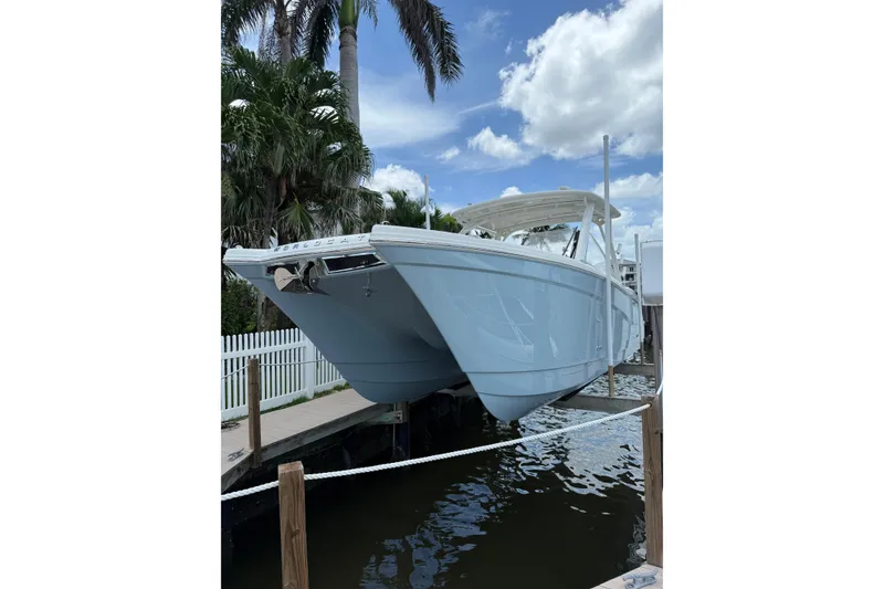 Slide: The Image of 2025 World Cat 280 DC-X boat docked, surrounded by palm trees and a clear sky. - 1