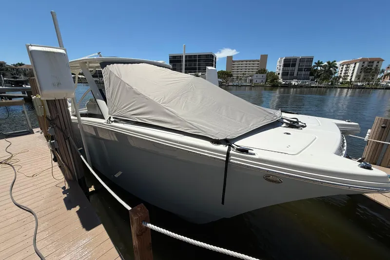 Slide: The Image of 2025 World Cat 280 DC-X boat docked with cover, urban waterfront backdrop. - 2
