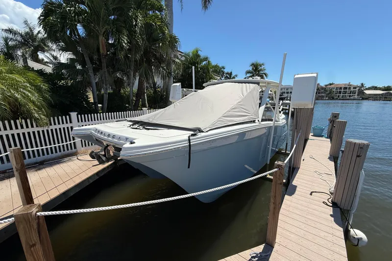 Slide: The Image of 2025 World Cat 280 DC-X boat docked by waterfront, covered and surrounded by palm trees. - 3