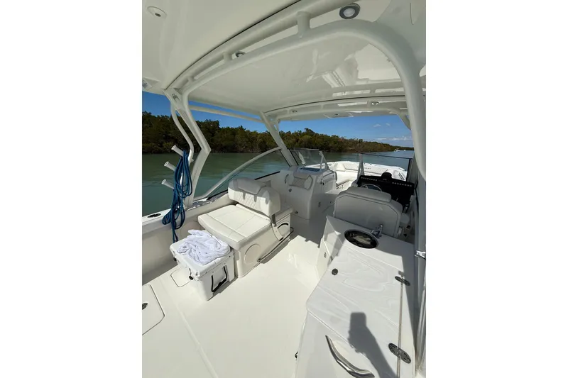 Slide: The Image of Interior of 2025 World Cat 280 DC-X boat, featuring seating and helm, on calm water. - 8