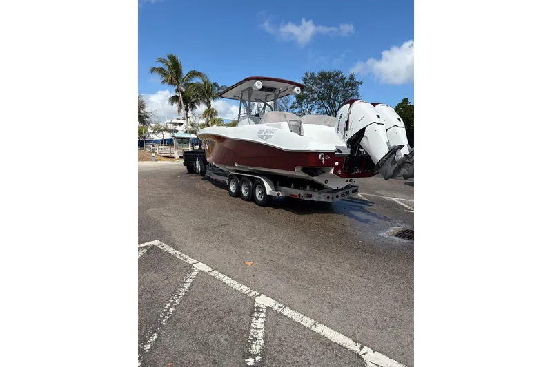 Slide: The Image of 2015 Deep Impact 33 boat on trailer, parked near palm trees under blue sky. - 4