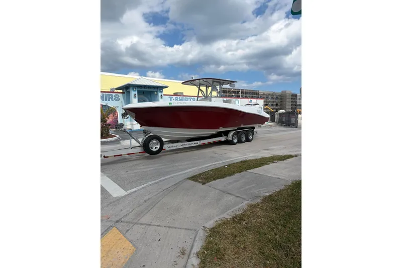 Slide: The Image of 2015 Deep Impact 33 boat on trailer, parked near colorful building under cloudy sky. - 5