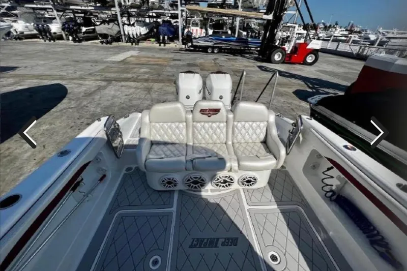 Slide: The Image of 2015 Deep Impact 33 boat interior with cushioned seating and speakers at a marina. - 8
