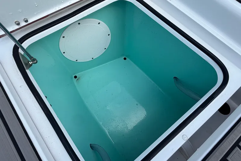 Slide: The Image of 2024 BlackJack 256 Bay boat storage compartment with turquoise interior and secure latch. - 27
