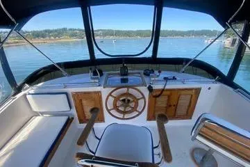 Slide: The Image of 1982 C @ L Sea Ranger boat cockpit with wooden steering wheel, overlooking serene waters. - 38