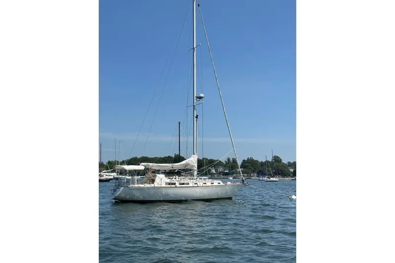 Slide: The Image of 1984 Sabre 38 sailboat anchored on calm water under clear blue sky. - 2