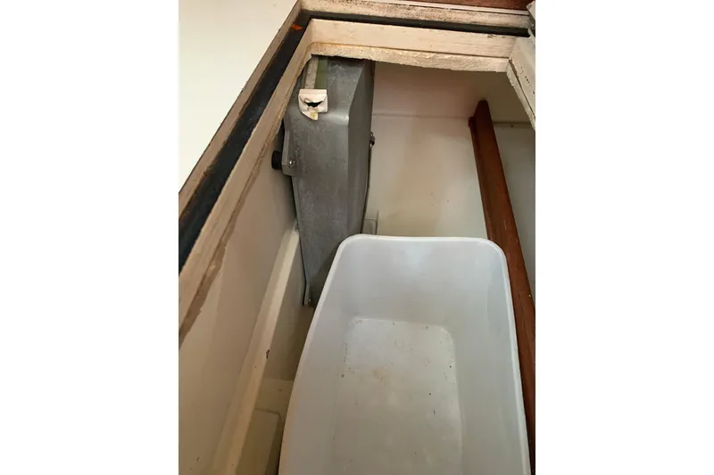 Slide: The Image of Storage compartment in a 1984 Sabre 38 sailboat with a plastic container. - 38