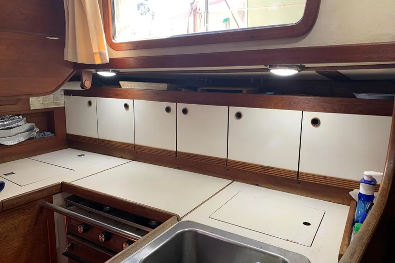 Slide: The Image of 1984 Sabre 38 yacht galley with wooden cabinets, stove, and sink. - 40
