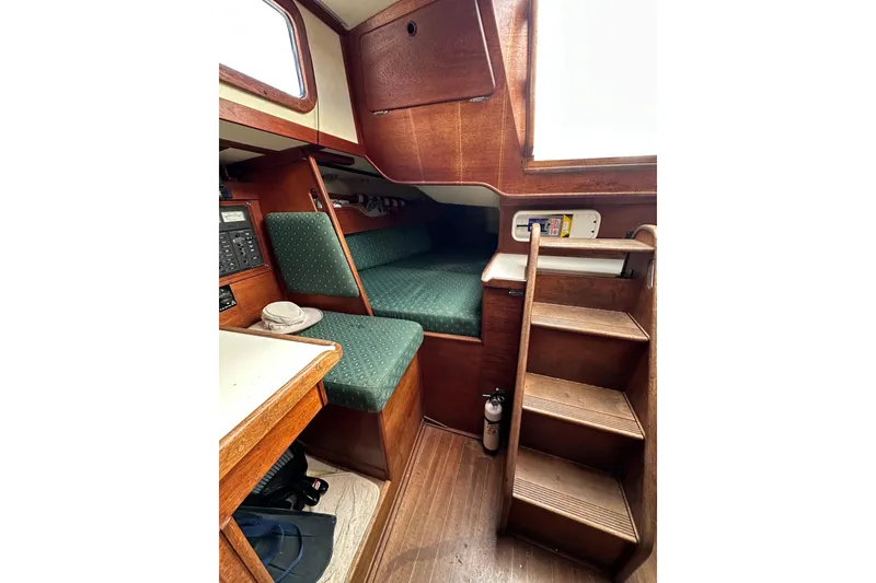 Slide: The Image of 1984 Sabre 38 sailboat interior with wooden finish, green upholstery, and compact stairs. - 43
