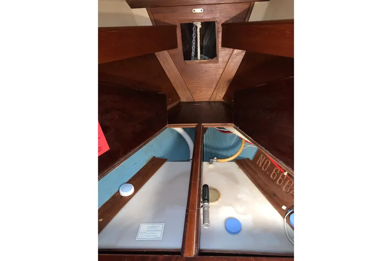 Slide: The Image of V-berth tank holding tank access in a 1984 Sabre 38 sailboat showing storage compartments and plumbing. - 48