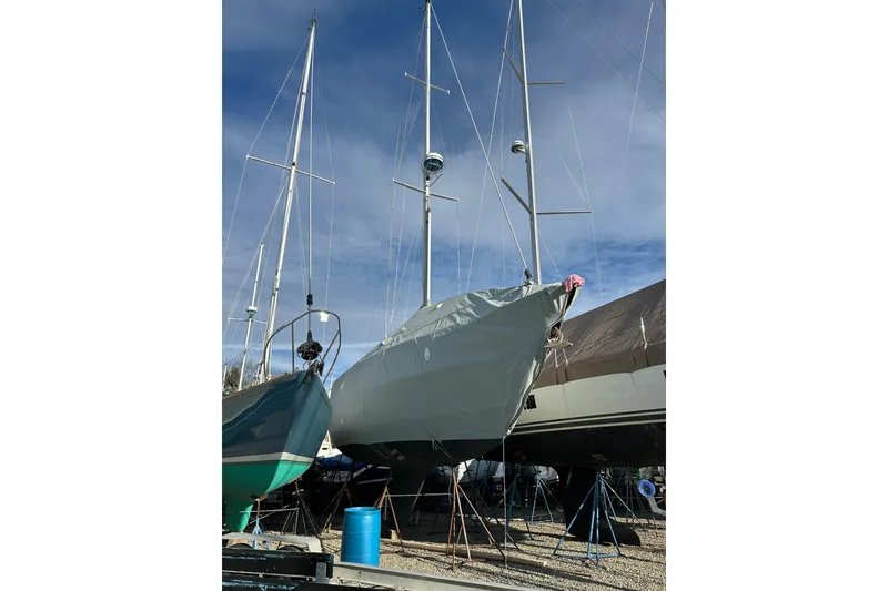 Slide: The Image of 1984 Sabre 38 sailboat on land, covered and supported, with clear blue sky. - 5