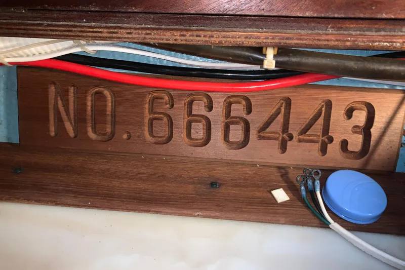 Slide: The Image of Wooden plaque with "NO. 666443" engraved, surrounded by wires, on a 1984 Sabre 38. - 53