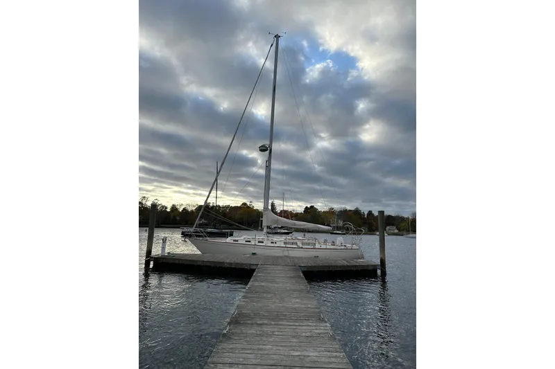 Slide: The Image of 1984 Sabre 38 sailboat docked under cloudy sky at a serene marina. - 67