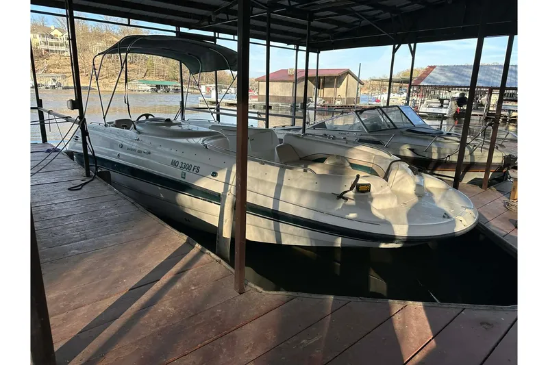 The Image of 1998 Chaparral Sunesta 252 boat docked in a marina under a covered slip. - 1