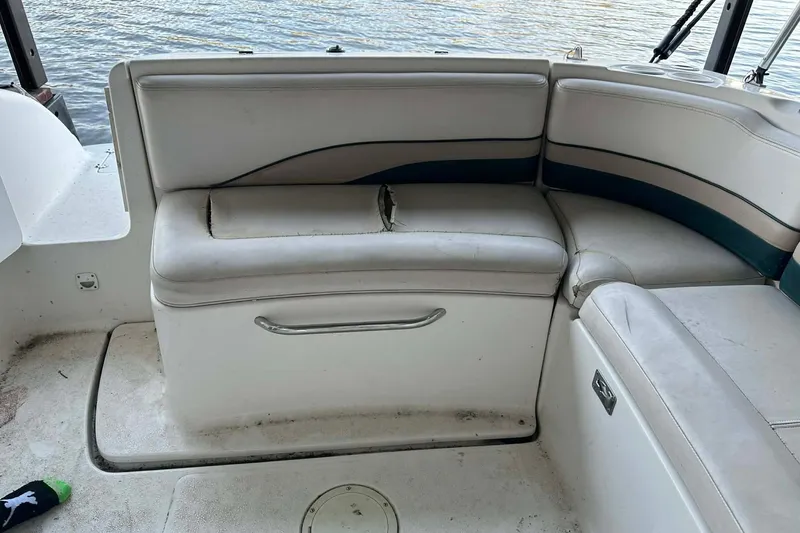 Slide: The Image of 1998 Chaparral Sunesta 252 boat interior with worn seating and visible water in the background. - 15