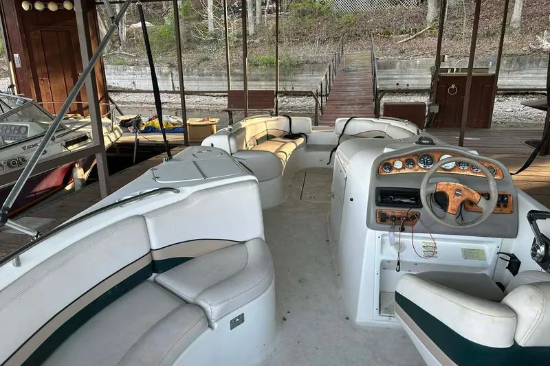 Slide: The Image of 1998 Chaparral Sunesta 252 boat interior with seating and steering wheel, docked in a covered area. - 18