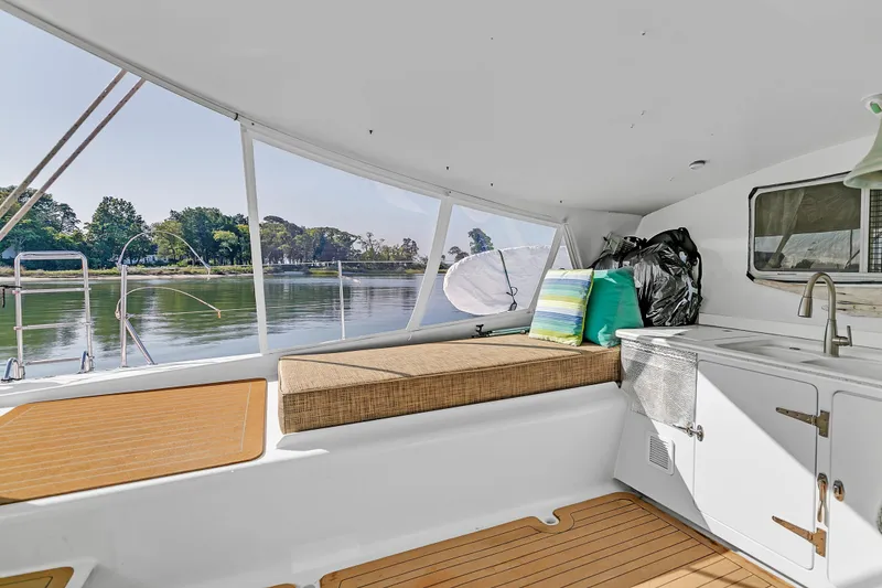 Slide: The Image of Interior of 1988 Kelsall Manannan Custom boat with seating and kitchenette, overlooking serene water. - 5