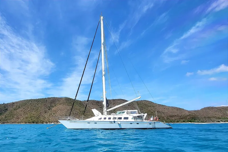 Slide: The Image of Sailing yacht "Kelsall Manannan Custom 1988" on blue ocean with scenic hills. - 56