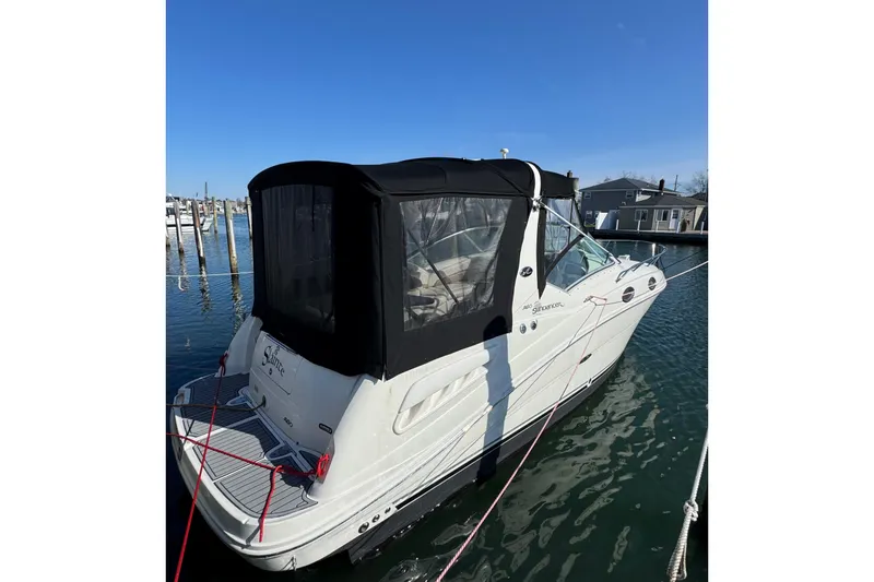 The Image of 2005 Sea Ray Sundancer 260 boat docked with black canopy, clear blue sky. - 0