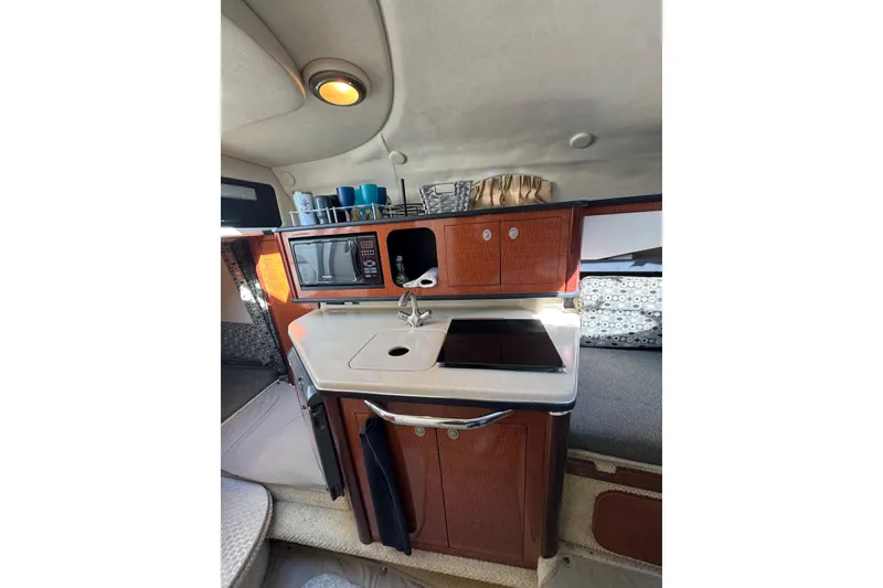 Slide: The Image of 2005 Sea Ray Sundancer 260 cabin kitchen with microwave, sink, and storage cabinets. - 15