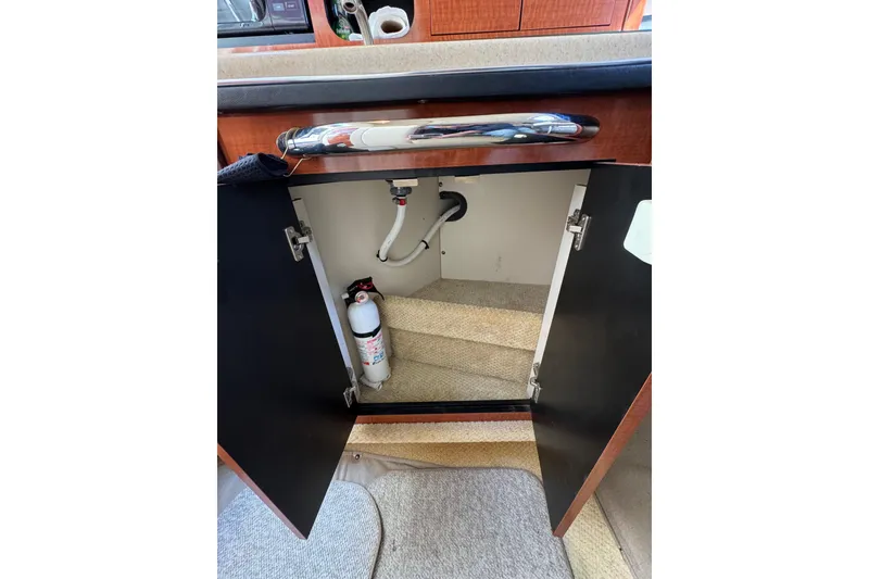 Slide: The Image of Open cabinet in 2005 Sea Ray Sundancer 260 boat interior, showing fire extinguisher and plumbing. - 16