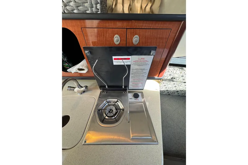 Slide: The Image of 2005 Sea Ray Sundancer 260 interior stove and sink area with wooden cabinetry. - 18