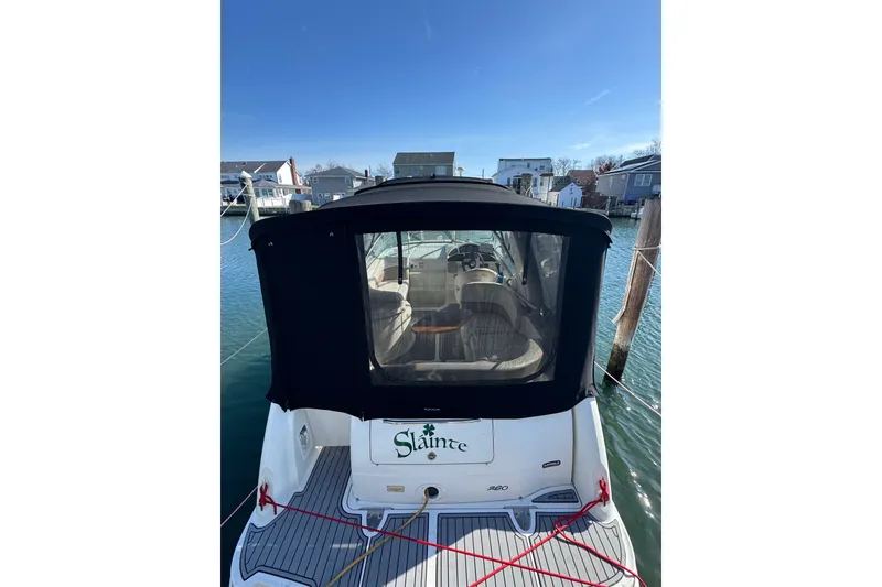 Slide: The Image of 2005 Sea Ray Sundancer 260 docked, featuring a black canopy and visible interior. - 2