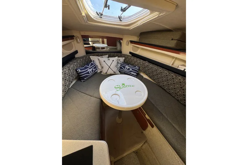 Slide: The Image of 2005 Sea Ray Sundancer 260 cabin interior with cozy seating and nautical-themed pillows. - 21