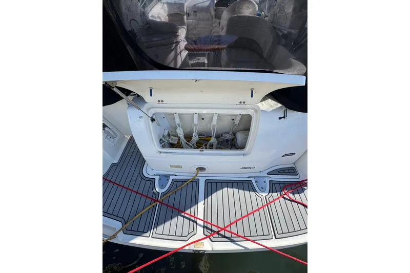 Slide: The Image of 2005 Sea Ray Sundancer 260 boat deck with open storage compartment and visible ropes. - 3