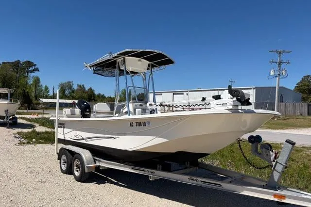 The Image of 2014 Carolina Skiff 218 DLV boat on trailer, parked outdoors under clear blue sky. - 0