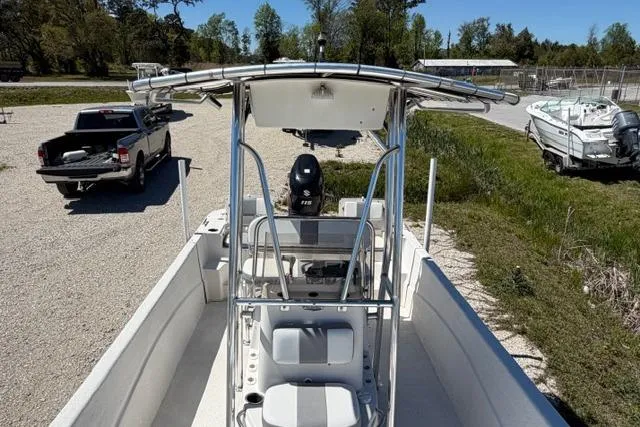 Slide: The Image of 2014 Carolina Skiff 218 DLV boat with T-top and outboard motor, parked on gravel. - 11