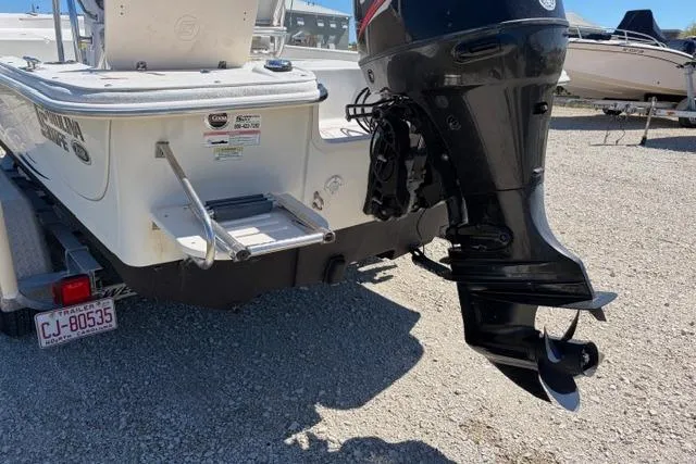 Slide: The Image of 2014 Carolina Skiff 218 DLV boat with outboard motor and trailer, parked on gravel. - 6