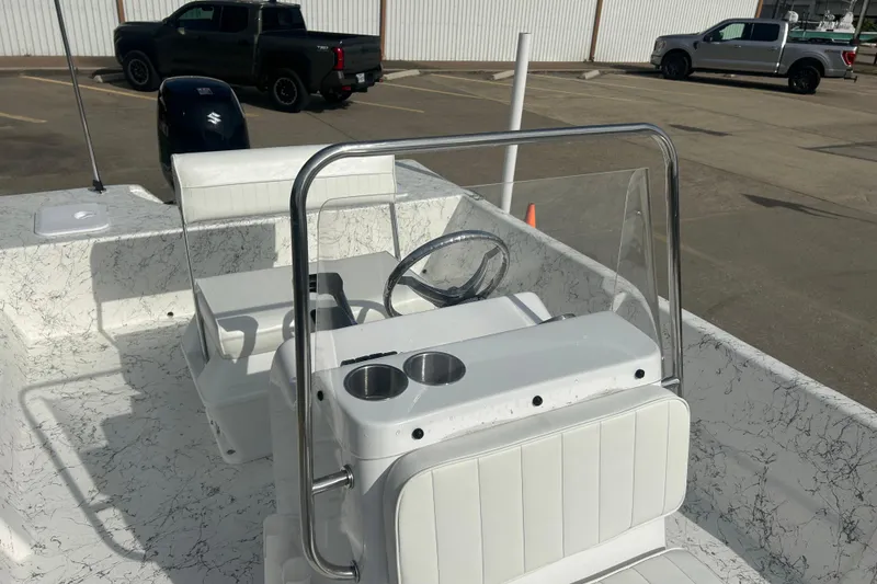 Slide: The Image of 2026 Coastal Skiff 184 boat interior with steering console and seating in a parking lot. - 10