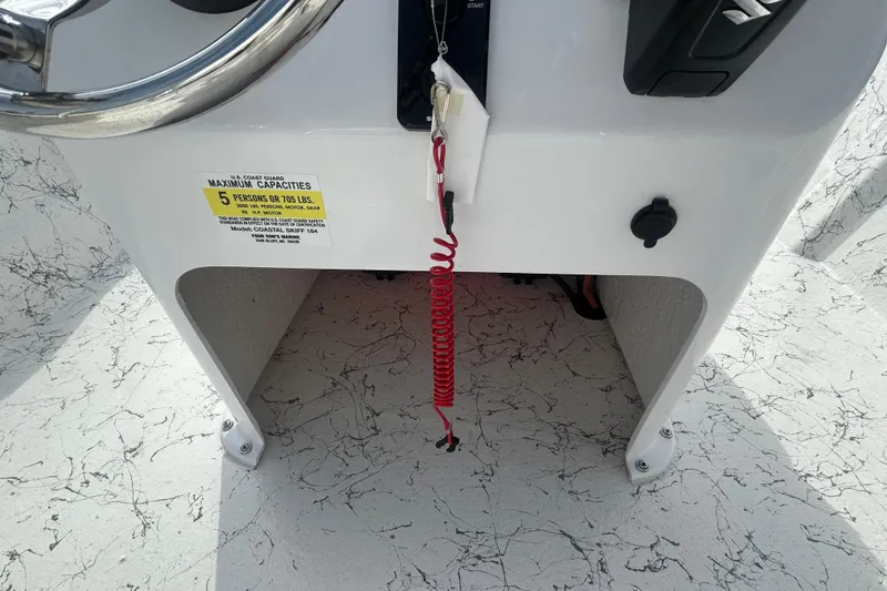 Slide: The Image of Console of 2026 Coastal Skiff 184 boat with capacity label and safety cord. - 18
