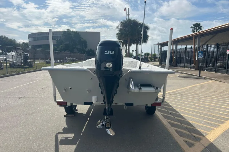 Slide: The Image of 2026 Coastal Skiff 184 boat with 90 HP engine on trailer, parked outdoors. - 2