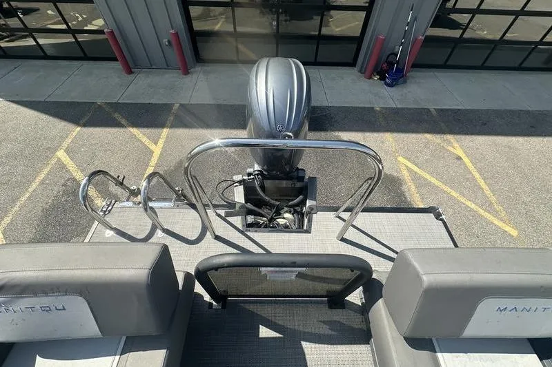 Slide: The Image of 2024 Manitou 24 X-Plode Cruise SHP boat with outboard motor and rear seating area. - 10