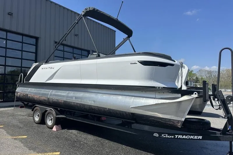 Slide: The Image of 2024 Manitou 24 X-Plode Cruise SHP pontoon boat on trailer outside a building. - 11
