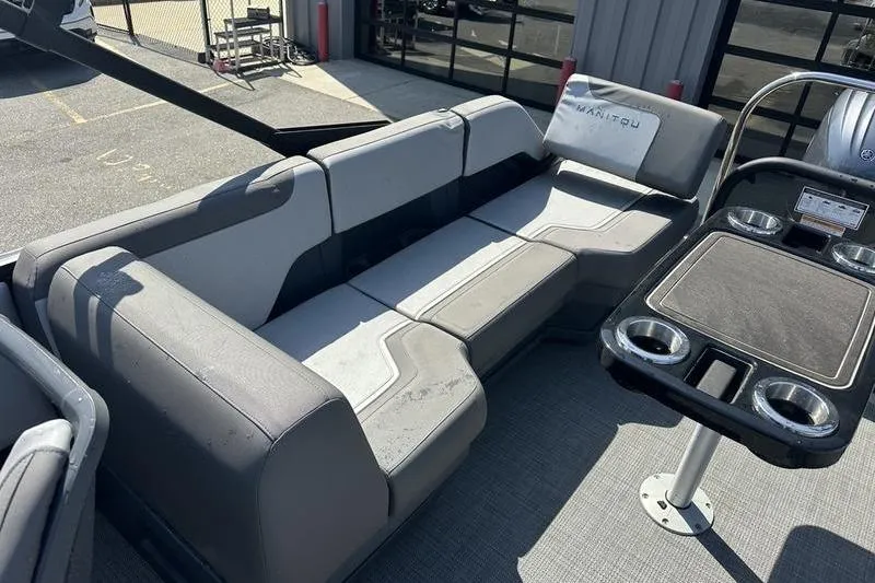 Slide: The Image of 2024 Manitou 24 X-Plode Cruise SHP boat interior with gray seating and cup holders. - 12