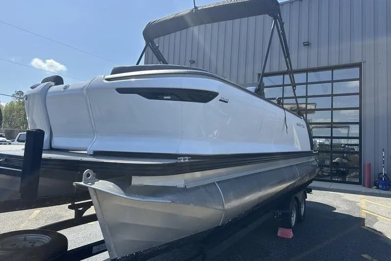 Slide: The Image of 2024 Manitou 24 X-Plode Cruise SHP pontoon boat on trailer outside a building. - 15