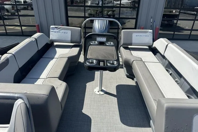 Slide: The Image of 2024 Manitou 24 X-Plode Cruise SHP pontoon boat interior with seating and table. - 2